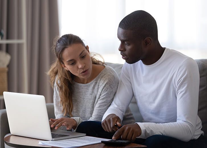 Millennial multiracial married couple calculating monthly family budget
